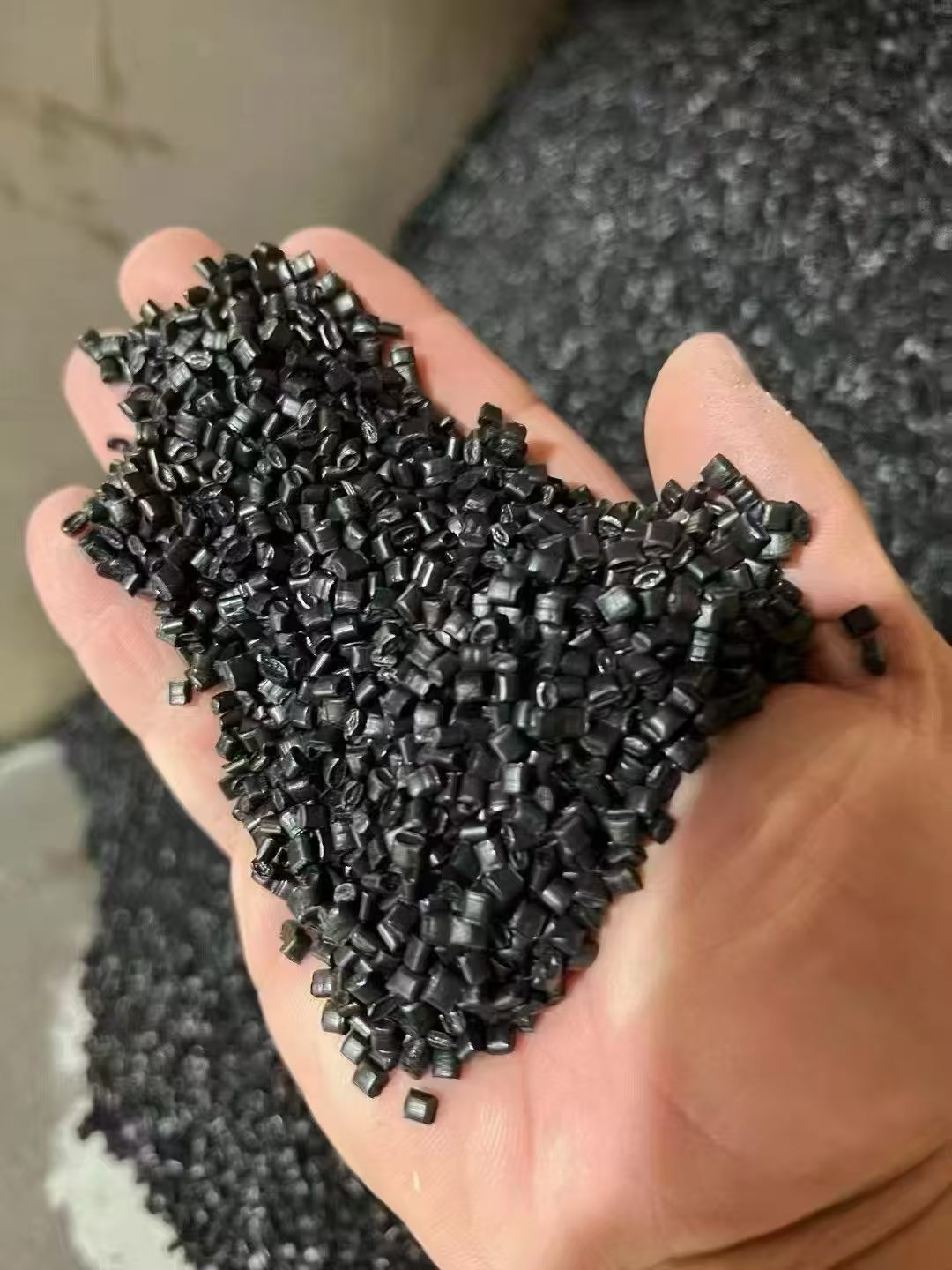 手掌展示的黑色再生塑料颗粒近景