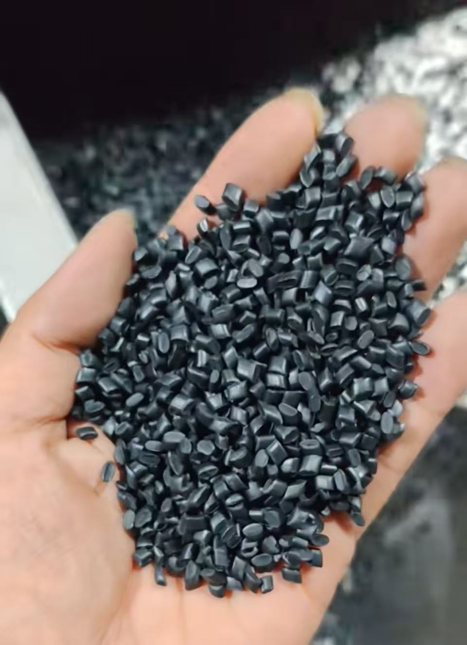 手掌展示的深灰色再生塑料颗粒