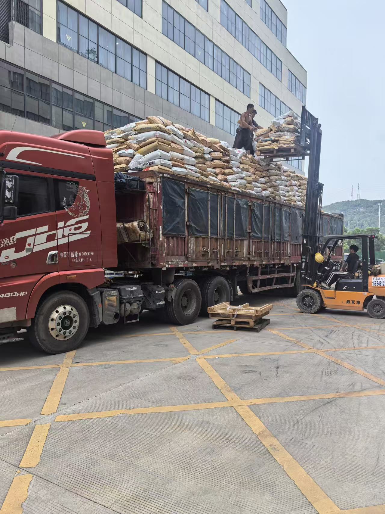 货车装货现场,工人与叉车配合装车